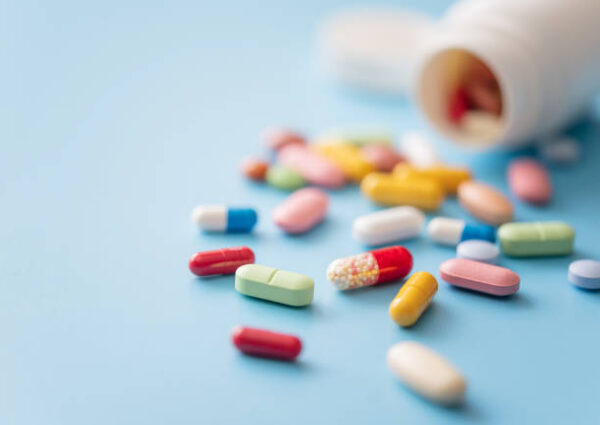 Colorful Pills scattered from white plastic pill bottle on blue background. Shallow DOF
